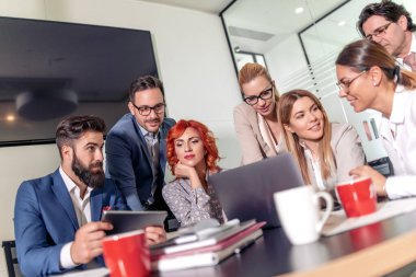 Bir grup iş adamı ofiste birlikte otururken çalışıyor ve iletişim kuruyor. 