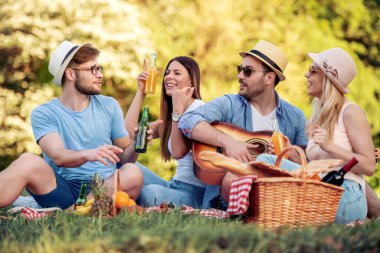 Yaz, tatil, müzik ve eğlence zamanı konsepti. Neşeli dört arkadaş doğada piknik yapıyor..