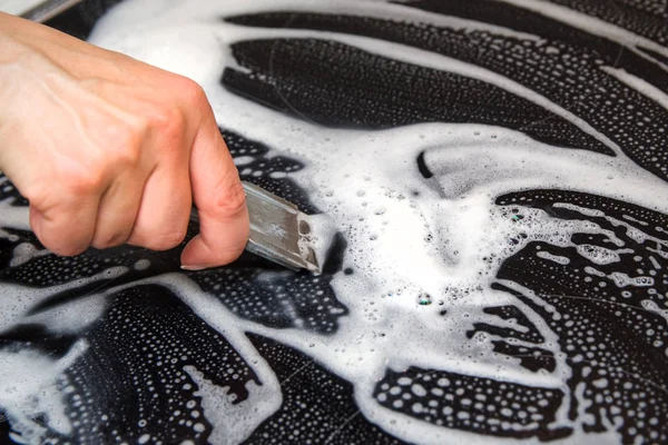 A woman cleans the electronic ceramic hob, using special steel scraper and detergent agent, applied to the surface of the hob. Chores and domestic labour concept.