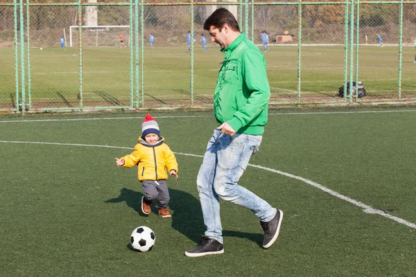 Молодой отец со своим маленьким сыном играет в футбол, футбол в парке — стоковое фото