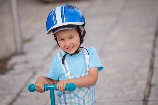 Niño feliz con casco, jugando con su scooter al aire libre — Foto de Stock