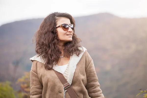 Junge lächelnde Frau, die allein in den Bergen im Hintergrund steht. Lebensstil. — Stockfoto