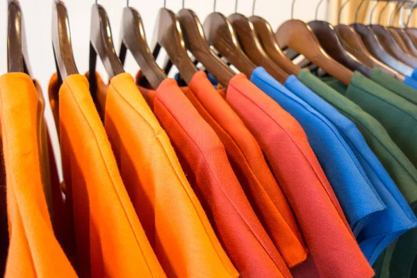 Линия разноцветной одежды на деревянных вешалках в магазине. Продажа — стоковое фото