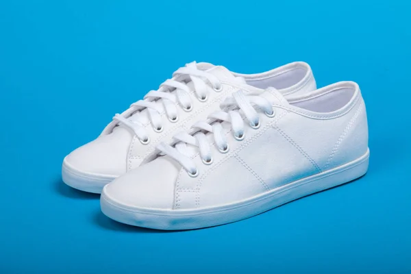 Par av nya vita sneakers på blå bakgrund — Stockfoto