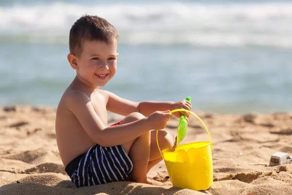 Mały chłopiec bawić się piaskiem na letniej plaży — Zdjęcie stockowe