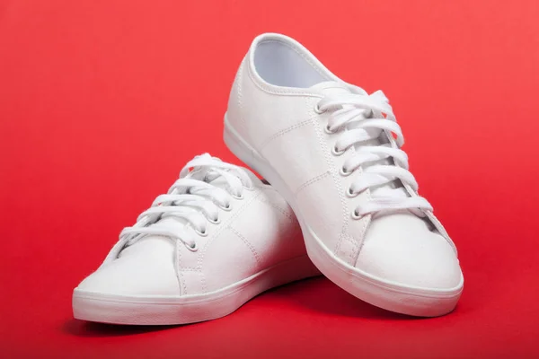 Coppia di nuove sneakers bianche su sfondo rosso — Foto Stock