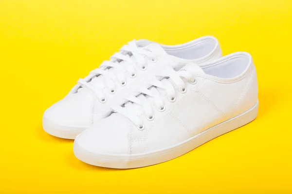 Pair of new white sneakers on yellow background — Stock Photo, Image