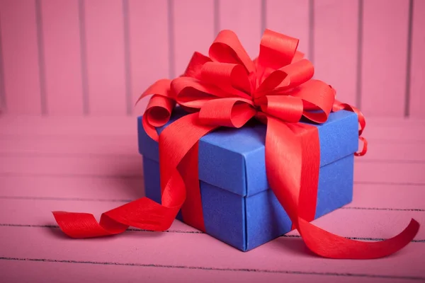 Blue gift box with red ribbon and bow on pink background — Stock Photo, Image