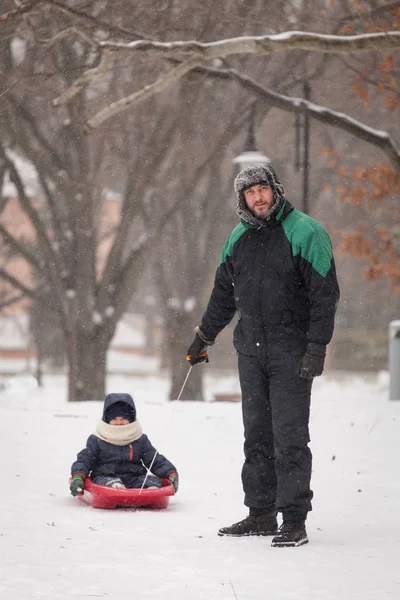 Mio padre tira un bambino su una slitta. Padre e figlio slittino in inverno . — Foto Stock