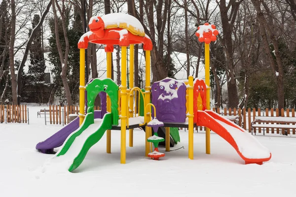 Parco giochi per bambini con neve vuota nel parco in inverno — Foto Stock