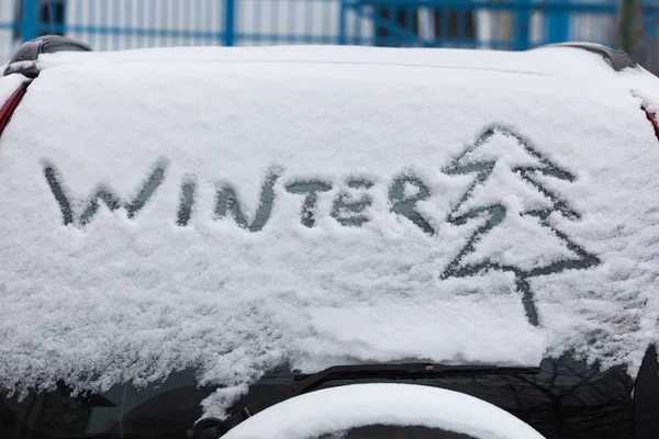 Надпись зима и дерево на снегу на заднем стекле автомобиля, внедорожник — стоковое фото