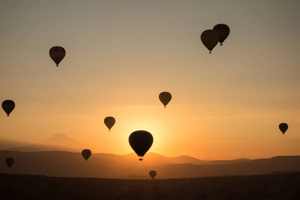 Balões de ar quente no céu durante o nascer do sol. Voando sobre o vale na Capadócia, Anatólia, Turquia. Montanhas vulcânicas no parque nacional de Goreme . — Fotografia de Stock
