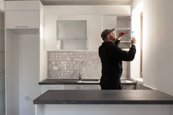 Carpentiere che lavora sulla nuova cucina. Handyman che fissa una porta in una cucina — Foto Stock