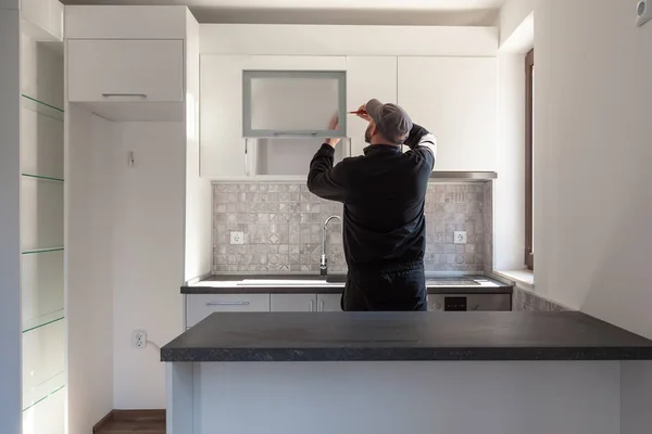 Carpentiere che lavora sulla nuova cucina. Handyman che fissa una porta in una cucina — Foto Stock