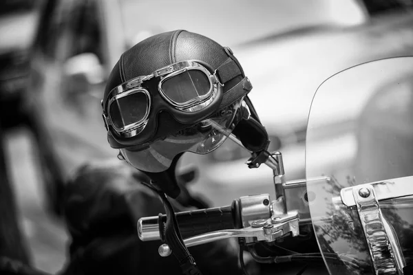 Vintage style motorbike helmet with goggles on the motorcycle handlebar. In Black and White — Stock Photo, Image