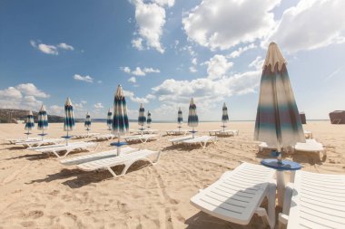 Birçok plaj sandalyeleri ve bulutlu mavi gökyüzü ile güzel plaj kapalı şemsiye