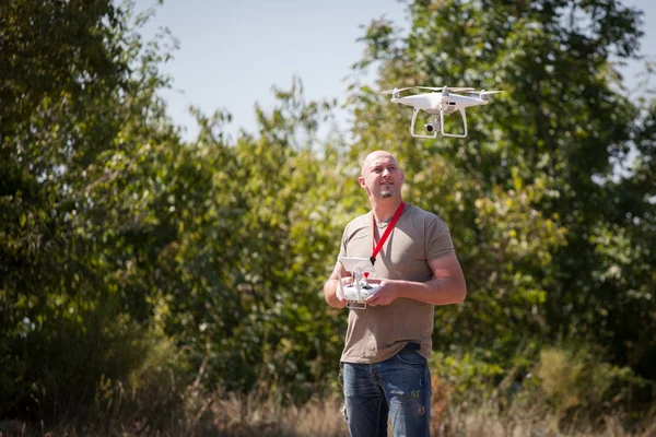 Giovanotto con drone volante nel parco. Uomo con telecomando in mano scattare foto aeree e video — Foto Stock