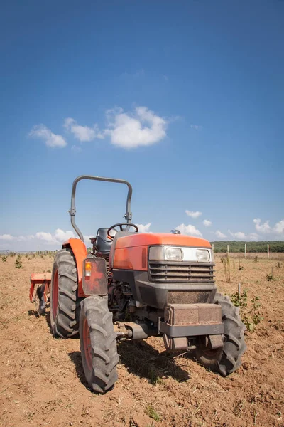 Kleiner roter Traktor mit Pflug im Feld. Bewölkter Himmel — Stockfoto