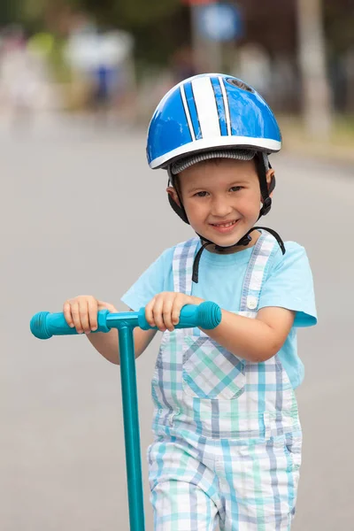 Niño feliz con casco, jugando con su scooter al aire libre — Foto de Stock