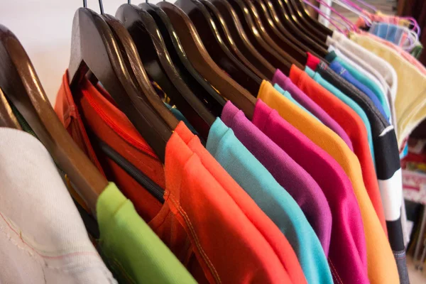 Reihe mehrfarbiger Kleidungsstücke auf hölzernen Kleiderbügeln. Verkauf — Stockfoto