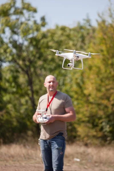 Giovanotto con drone volante nel parco. Uomo con telecomando in mano scattare foto aeree e video — Foto Stock