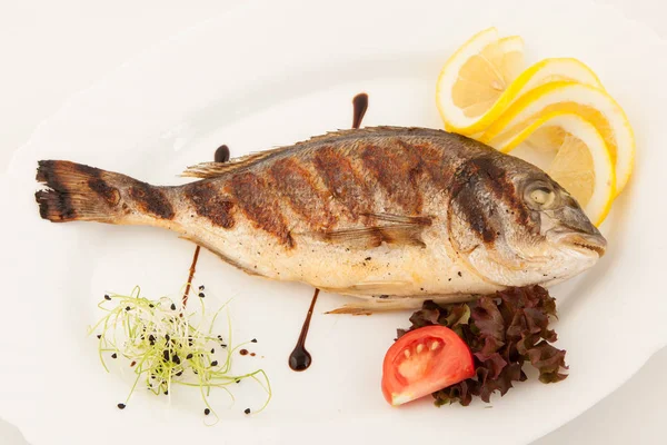 Grilovaná ryba na bílém štítku s bylinkami a citronem, pohled shora. Mořské plody Středomořská. — Stock fotografie