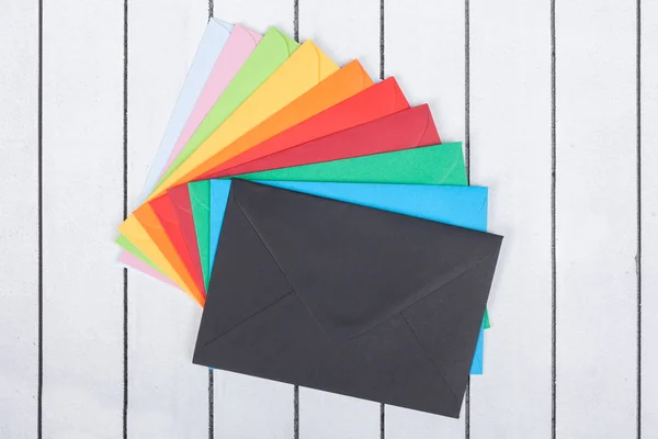 Багатокольорові конверти на білому дерев'яному фоні — стокове фото
