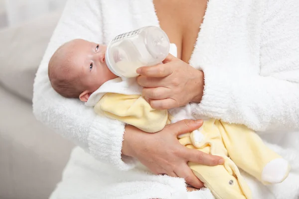 Anya tejes üveggel tartja és eteti az újszülöttet. Meghitt pillanat anya és baba között.. — Stock Fotó