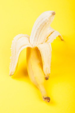 Sarı arka planda yarı soyulmuş muz.