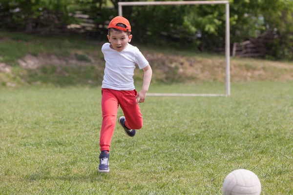 公園でボールを蹴っている小さな男の子。公園でサッカー (フットボール)。運動や活動のためのスポーツ. — ストック写真