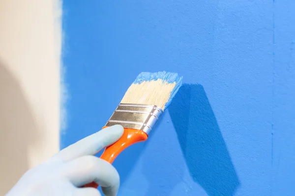 Primer plano de la mano masculina en guantes pintando una pared con pintura azul. Reparación y renovación del hogar concepto —  Fotos de Stock