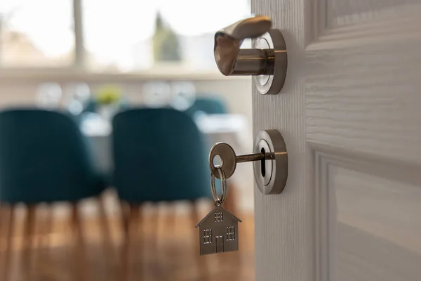 打开新家的大门。门把手与钥匙和家庭形状的钥匙链。抵押贷款、投资、房地产、财产和新住房概念 — 图库照片