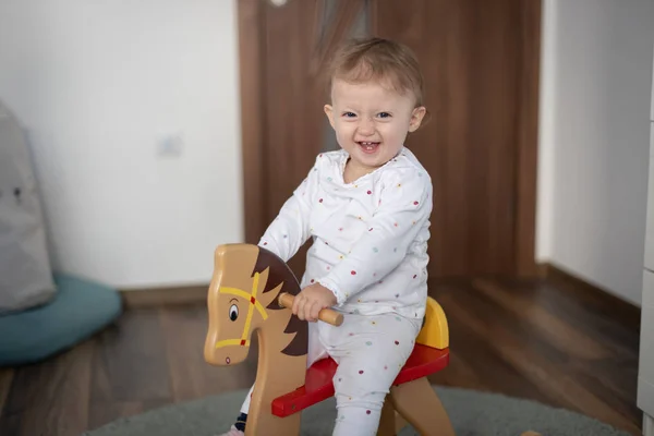 Happy baby girl bermain di kuda goyang kayu. Childhood, permainan di rumah konsep — Stok Foto