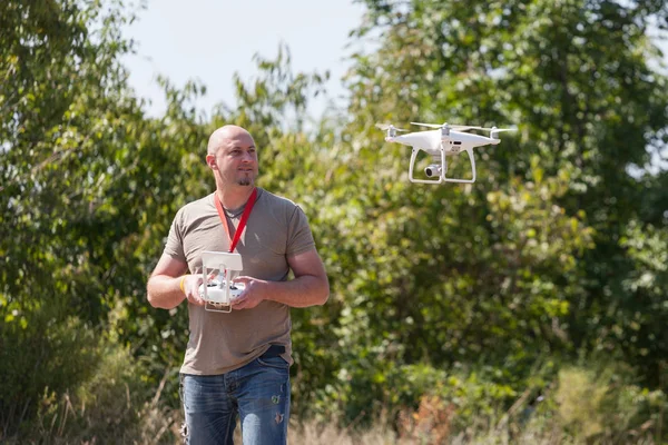 Un uomo con un drone volante nel parco. Uomo con telecomando in mano scattare foto aeree e video — Foto Stock