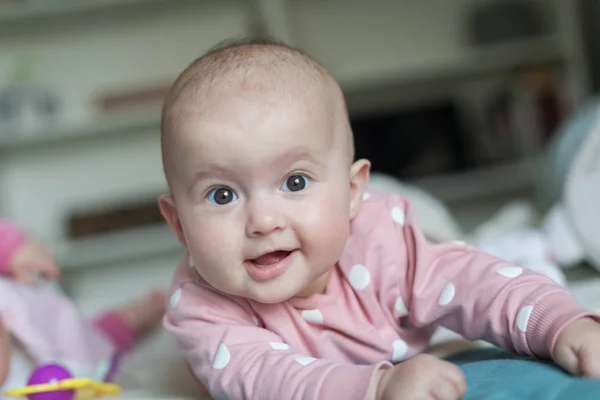 Çekici bir bebeğin portresi yüzüstü yatıp gülüyor. Aile sabahı evde. Mide zamanı. — Stok fotoğraf