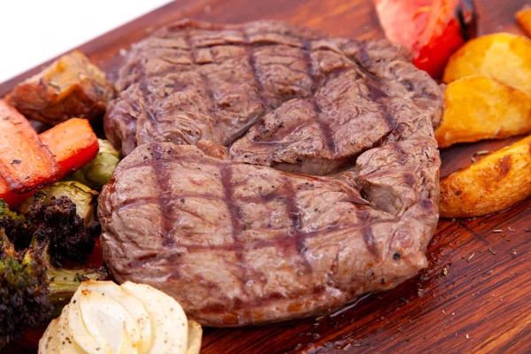 肉は野菜と一緒にリバイを焼きます。木の板の上のリバイステーキ。閉じろ! — ストック写真