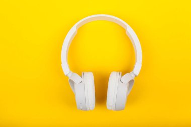 Sarı zemin üzerine beyaz kablosuz kulaklık. Müzik konsepti. Sarı arka plan üzerinde kulaklık. 