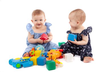 İki sevimli kız bebek oyuncaklar ile oynarken, beyaz izole
