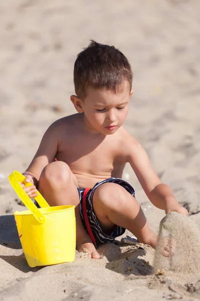 Mały chłopiec bawi się piasek na plaży latem — Zdjęcie stockowe