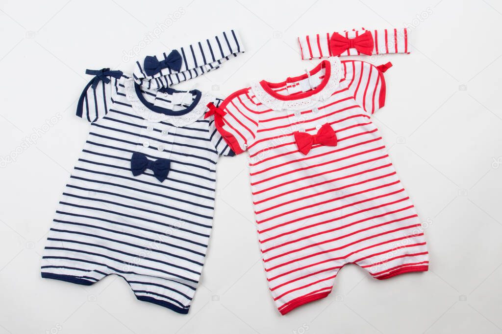 Cute baby clothes on white background. Blue and red bodysuits and hairbands, ribbons.