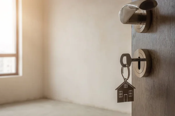 Abra a porta para uma nova casa. maçaneta da porta com chave e chaveiro em forma de casa. Hipoteca, investimento, imobiliário, propriedade e novo conceito de casa — Fotografia de Stock