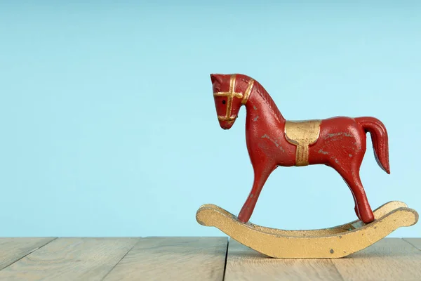 Red vintage rocking horse on wooden floor. Blue background
