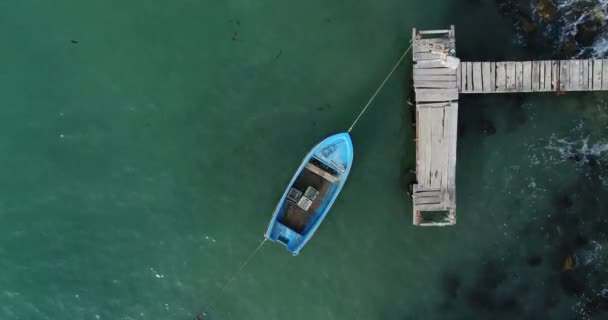 4K空中视频孤零零的渔船和木制码头在碧绿的海洋 顶部视图 — 图库视频影像