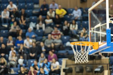 Arka planda taraftarları olan basketbol tahtası ve sepeti. Seyircilerin arka planında basketbol sepeti. 