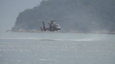  Askeri, kurtarma helikopteri bir kurtarma görevi sırasında suyun üzerinde alçaktan süzülüyor. Kurtarma helikopteri alçaktan dönüyor. Yavaş çekim 