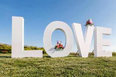 Aşk kelimesi büyük beyaz harflerle. Aşkın işareti, düğün konsepti.