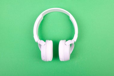 Yeşil arka planda kablosuz beyaz kulaklık. Müzik konsepti. Yeşil arka planda kulaklıklar. 