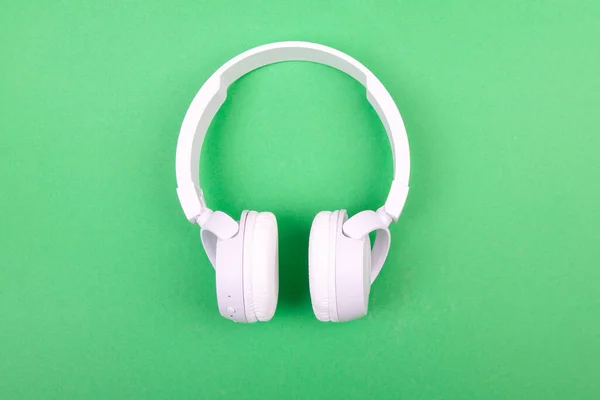 Wireless white headphones on green background. Music concept. Earphones on green background.