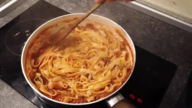 Bolonez spagetti pişiriyorum. Tavada spagetti ve sos karıştıran kadın.