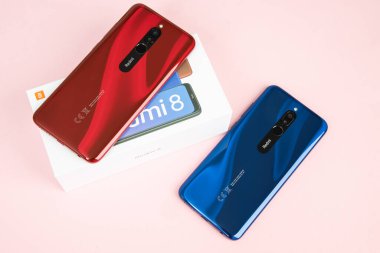 Varna, Nulgaria - 16 Mayıs 2020: Xiaomi Redmi 8 Android 'in arkasında Ruby Red ve Sapphire Blue renklerinde pembe arka plan. Redmi, Çinli elektronik şirketi Xiaomi 'ye ait bir markadır..